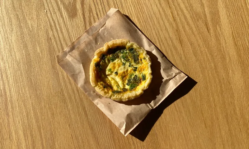 an aerial view of a round spinach and feta quiche on a wooden table