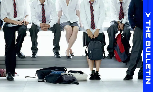 Five students in school uniforms sit on a bench, their faces out of frame. Backpacks rest on the floor in front of them. A blue vertical banner on the right reads "The Bulletin.