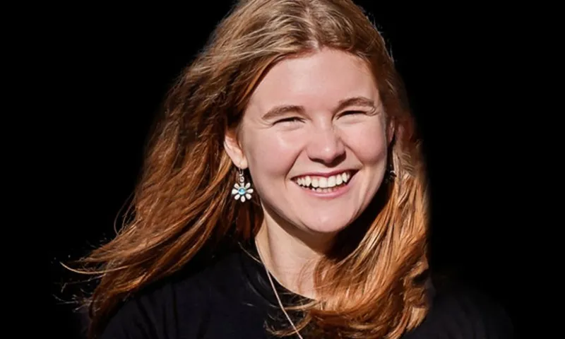 Headshot of Lily Carrington smiling against a black background.