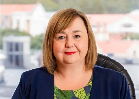 a white woman with medium brown hair in a bob and houses behind here