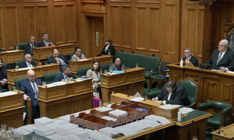 Screenshot from Parliament TV of the government benches, showing Simon Court removing his pin.