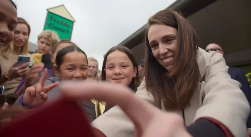 A photo showing Jacinda Ardern surrounded by kids and taking a selfie.
