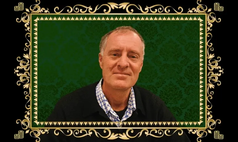 a white man in a collared shirt and sweater with a black and green background and gold frame around him