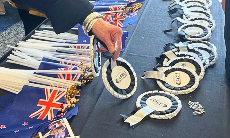 A display table with miniature New Zealand flags and NZ First badges.