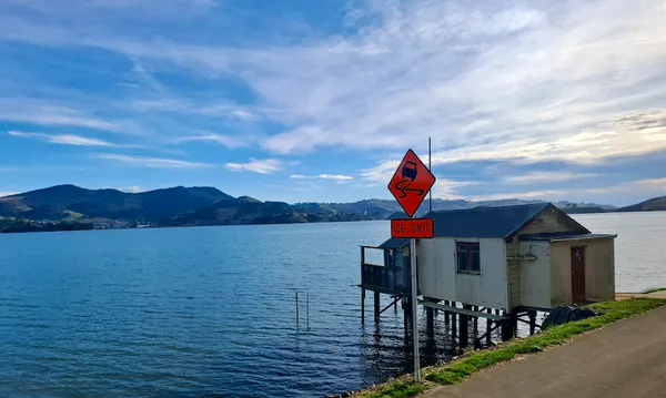 A boat shed on the Otago peninsula, with an orange sign saying "ice/grit" next to it