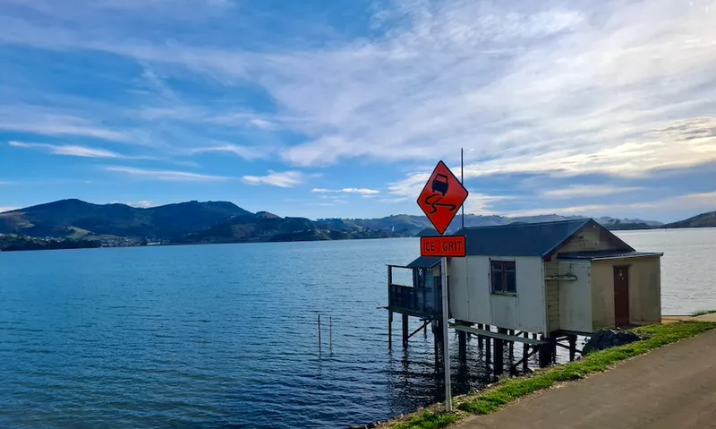 A boat shed on the Otago peninsula, with an orange sign saying "ice/grit" next to it