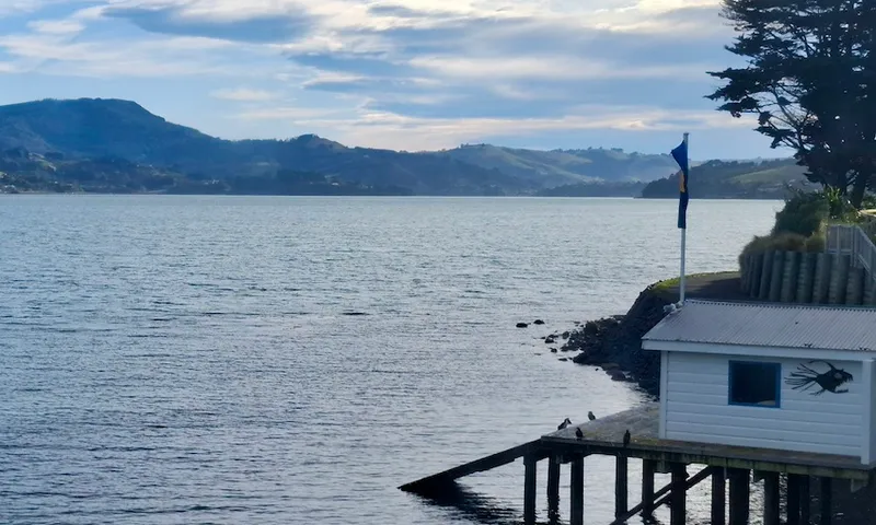 A picturesque scene of the sea and a boat shed, located on Otago Peninsula