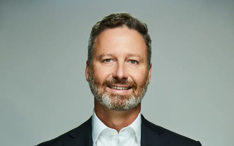 a man with a beard and short hair smiles at the camera