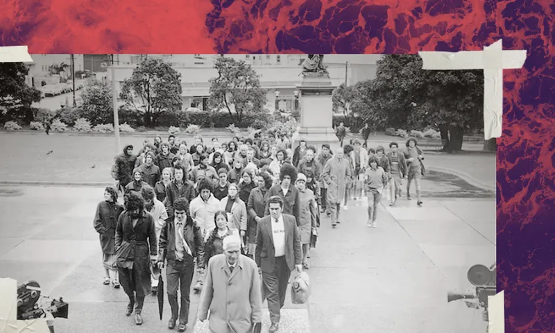 A large group of people marches together outdoors toward a building, with trees and a statue in the background. The black-and-white photo is bordered by colourful, marbled patterns and taped corners.