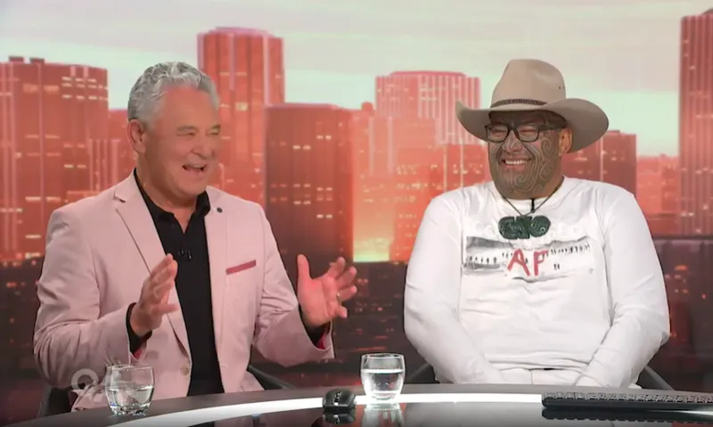 John Tamihere and Rawiri-Waititi laugh together while sitting on a panel for TVNZ's Q+A.