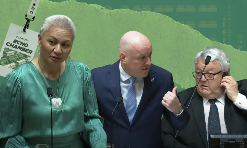 Three people dressed formally stand at podiums against a green background. The woman on the left wears a teal dress, the man in the middle gestures with his thumb, and the man on the right adjusts his glasses. A lanyard is visible at the top left.