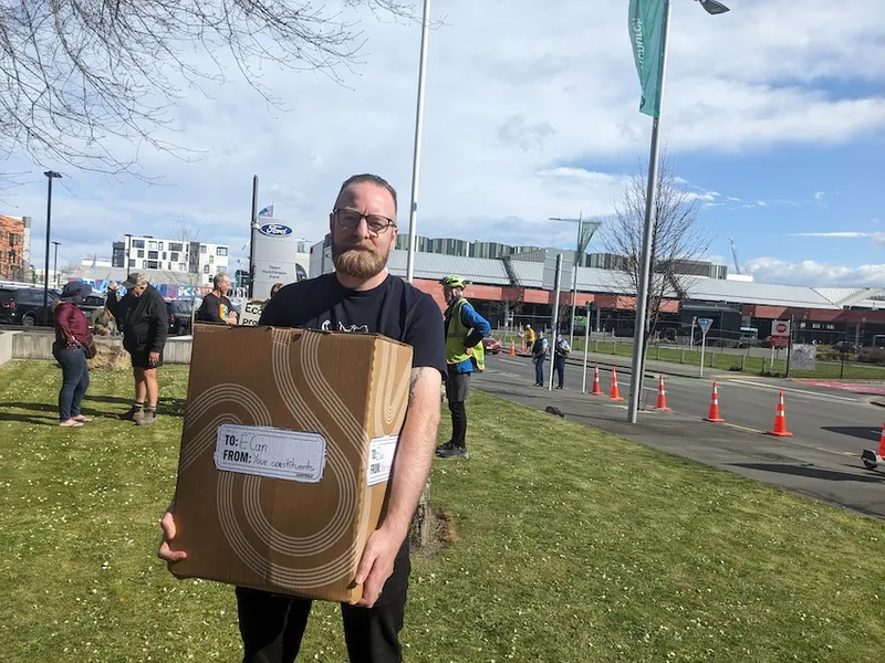 a man with puled back hair holding a cardboard box