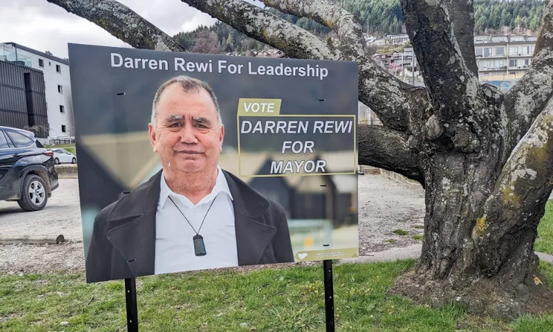 a serious looking Māori man with a sign saying "darren Rewi For Leadership"
