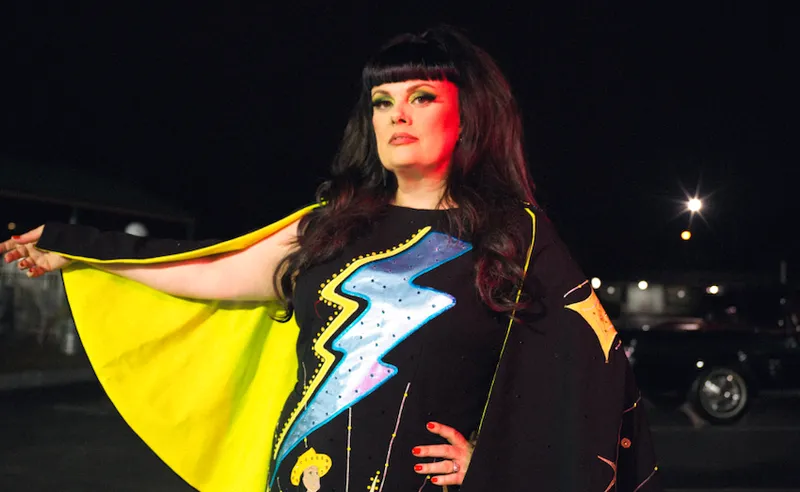 Tami Neilson in a black dress with blue sequin lightning bolt and neon yellow cape