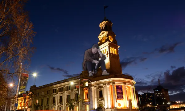 Hayden sitting crying on the town hall with a bottle of Jacob's Creek