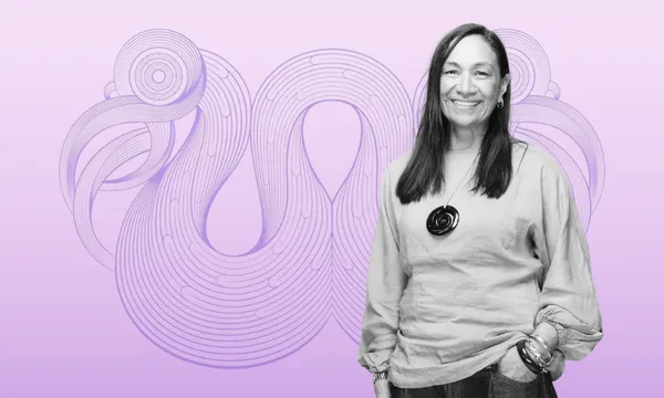A smiling woman with long hair stands in front of a purple abstract swirl design on a gradient lavender background. She wears a light blouse, pants, and a round pendant necklace.