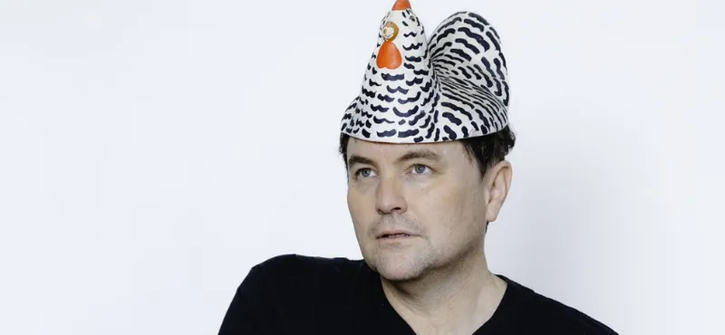 The actor Tom Sainsbury is in the middle of the frame wearing a chicken (fake) on his head.
