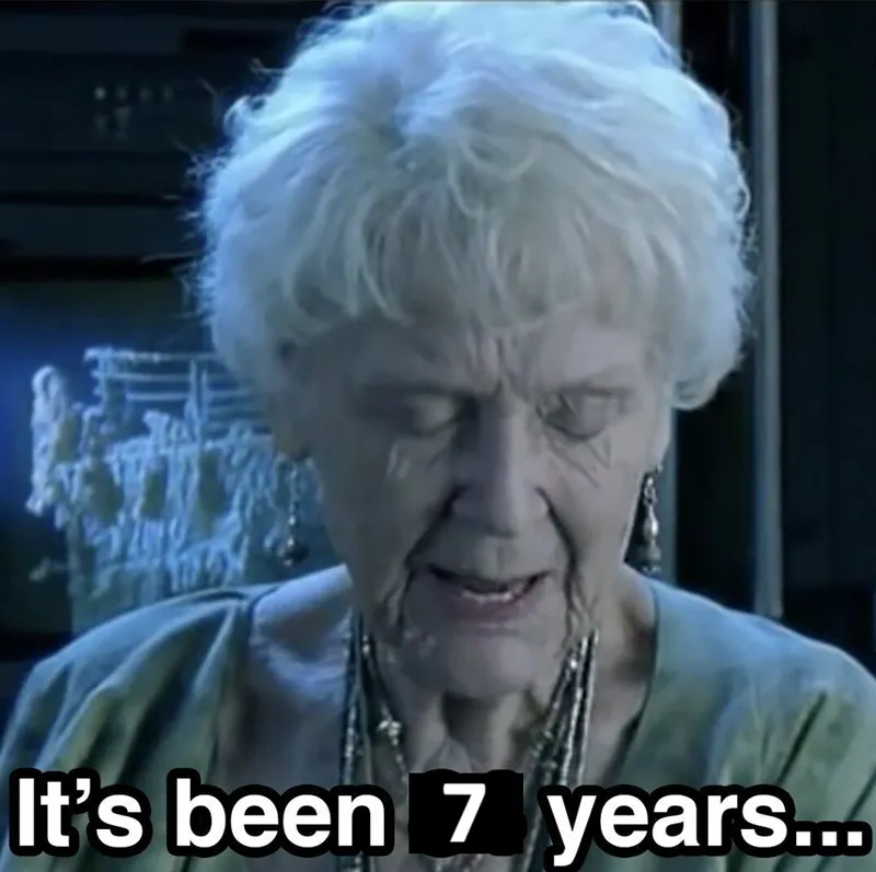 An elderly woman with white hair looks down sadly, with the text “It’s been 7 years…” in bold letters at the bottom of the image.