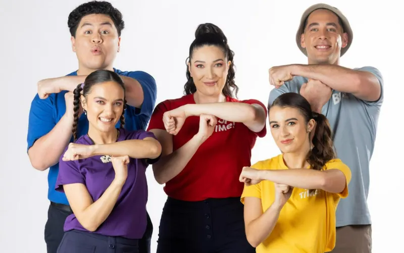 Five people wearing colourful tshirts against a white background, all making T shapes with their arms