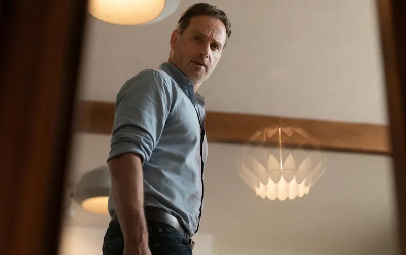 A low angle shot of Andrew Lincoln looking at the camera with a lampshade behind him