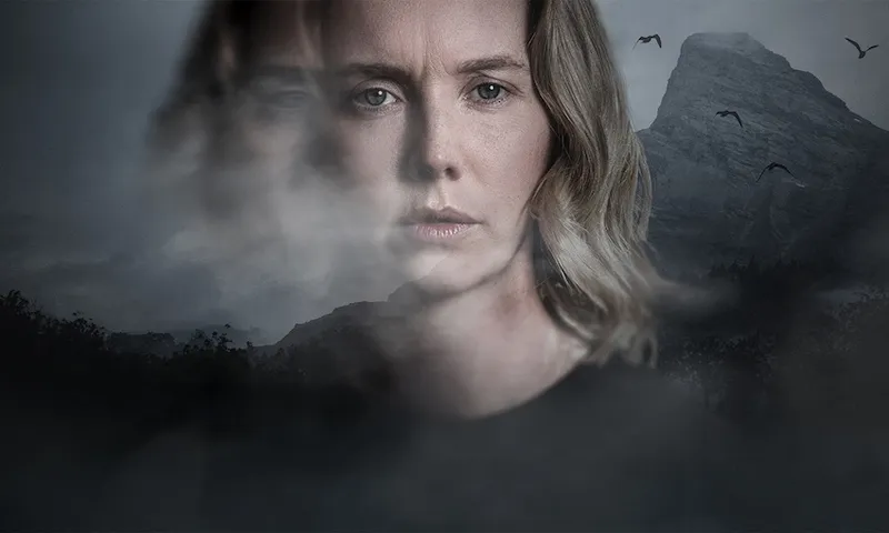 A blonde haired woman stares at the screen, with a moody landscape scene behind her