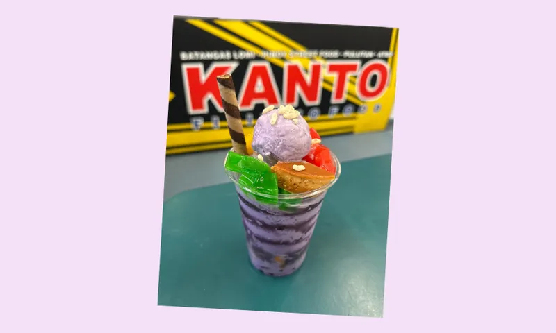 A cup of ice dessert with colourful fruit toppings in front of a Kanto sign