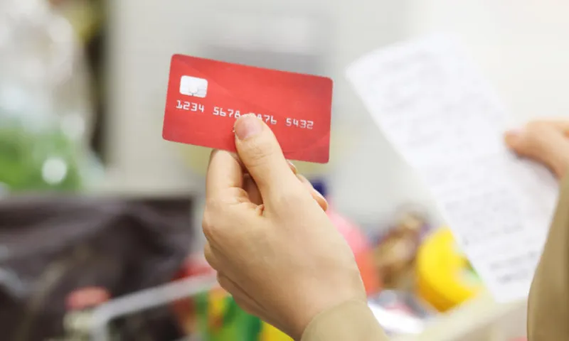 Close up of woman holding credit card with shopping list  in supermarket