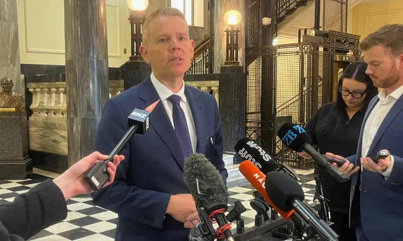 Chris Hipkins stand in front of a row of microphones on parliament's tiles to take questions.