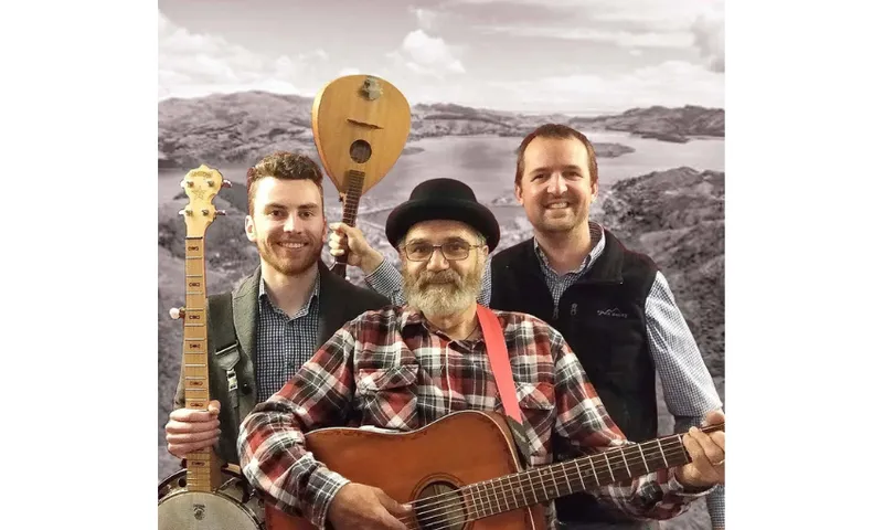A photo of a three piece band with a guitar and banjo visible.
