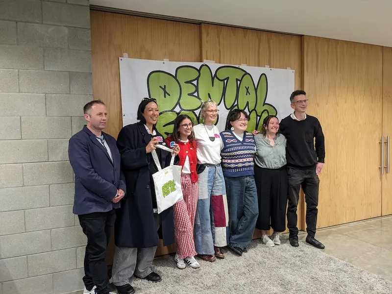 people standing in front of a banner reading Dental For all, smiling