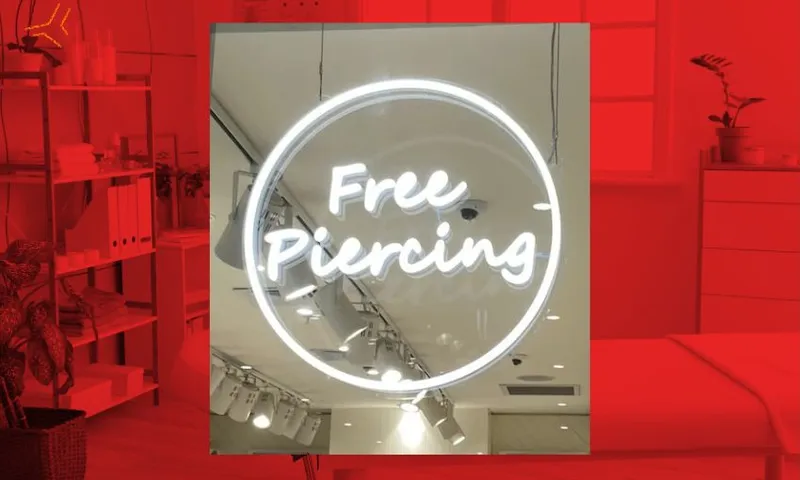 A red-tinted beauty salon in the background and a neon 'free piercing' sign in the foreground