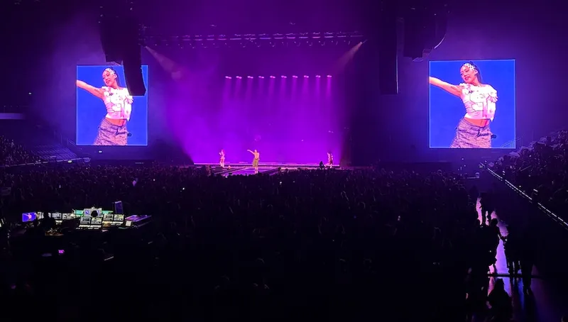A purple lit stage with Sailorr, dressed in pink, standing in the middle