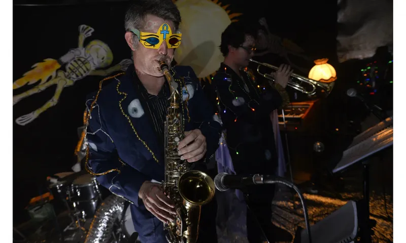 A photo of a man playing a saxophone and wearing a mask.