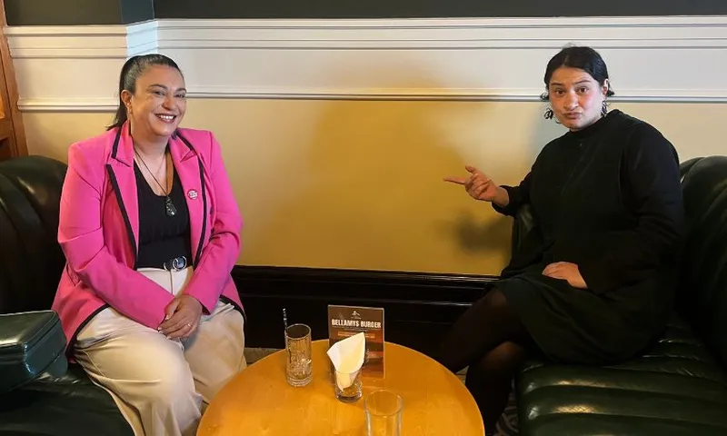 Karen Chhour sits on a green couch across from the author, smiling.