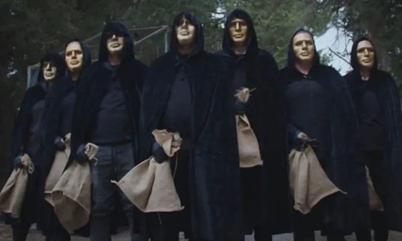 A line of cloaked figures in gold masks holding empty sacks on The Traitors NZ