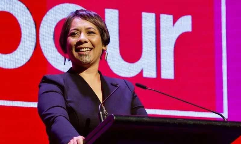Labour MP Cushla Tangaere-Manuel smiles while standing behind a podium, with the Labour Party logo behind her.