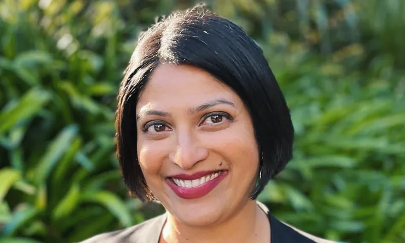Headshot of Priyanca Radhakrishnan, standing in front of greenery.