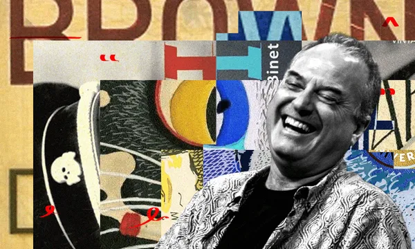 A black and white photo of a man laughing. He is middle-aged and wearing a checked shirt. Behind him is a collage of book covers.
