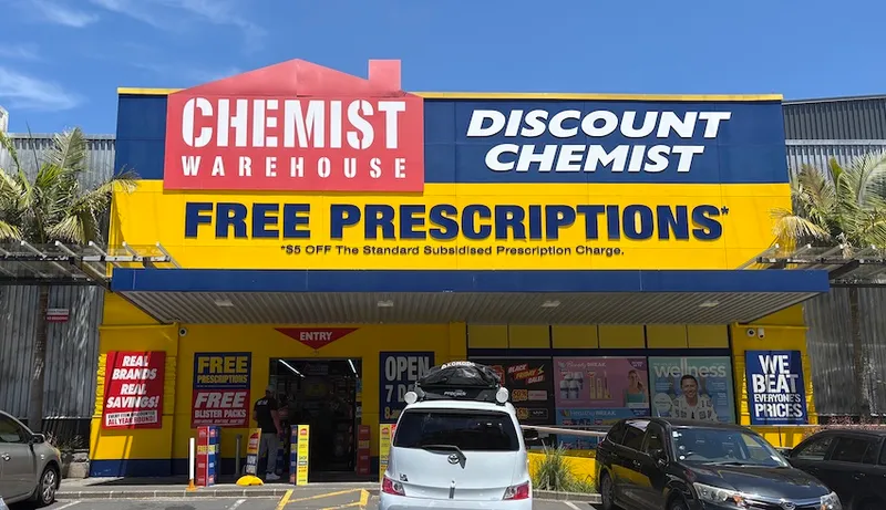 A bright yellow Chemist Warehouse against a blue Auckland sky