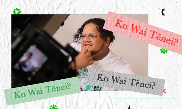 A person with curly hair, glasses, and a beard sits smiling while being filmed, with “Ko Wai Tēnei?” written in red, green, and gray text banners on the image.