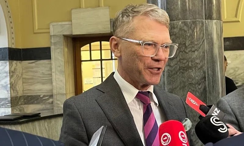 A headshot of Paul Goldsmith speaker into reporter's microphones.