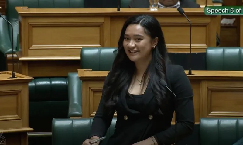 Hana-Rawhiti Maipi-Clark smiles as she stands in the House, behind her bench.