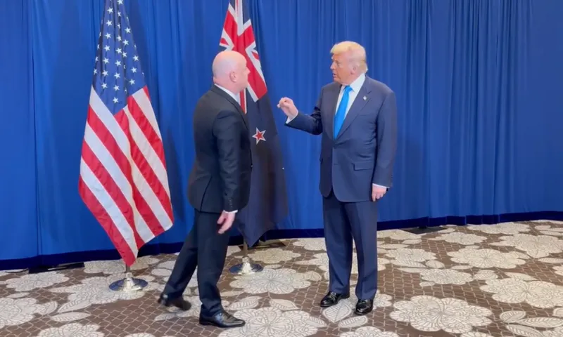 Christopher Luxon, with his back turned to the camera, speaks to US president Donald Trump.