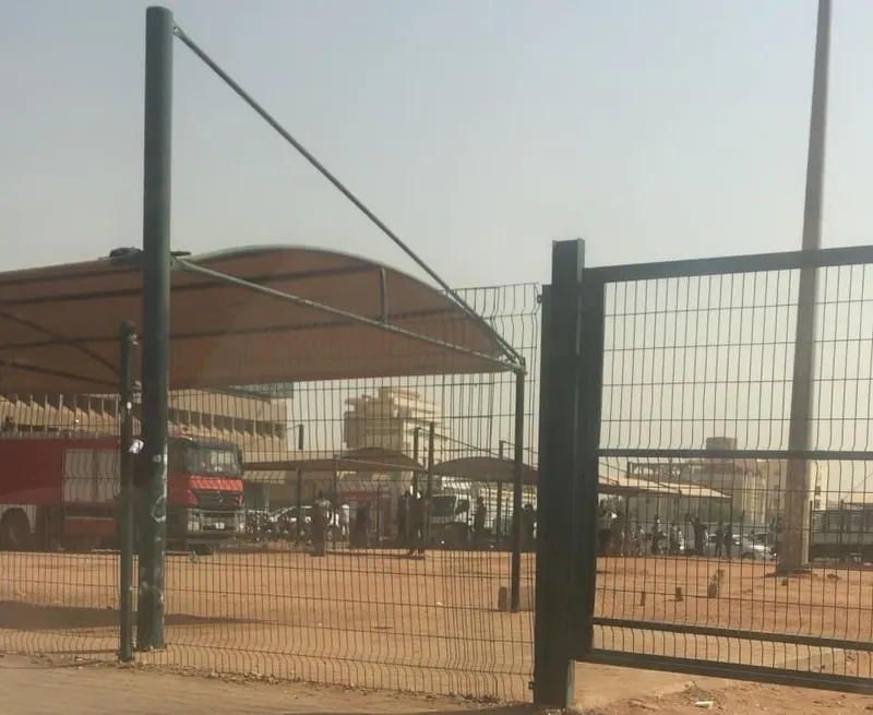 a covered bus station through a wire fence hazy air