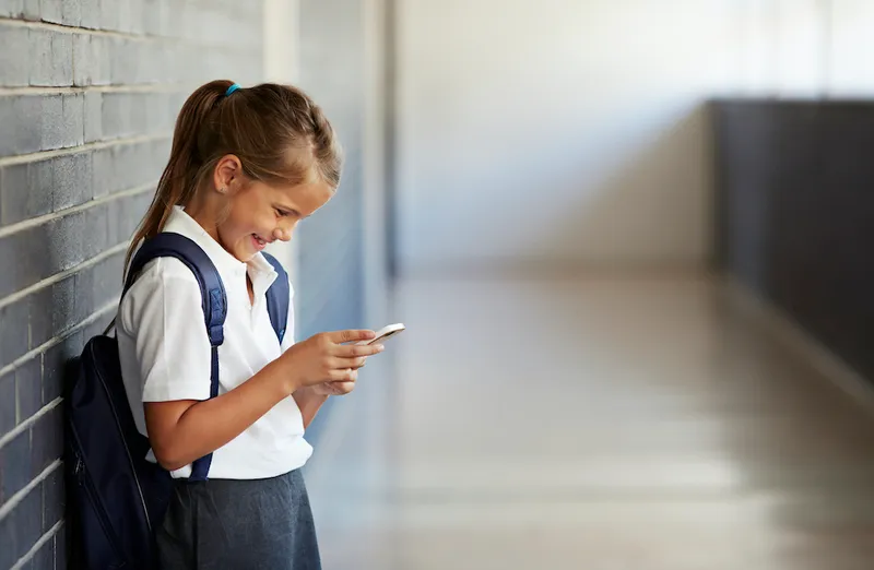 Schoolgirl looking at phone and smiling