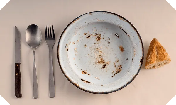 Empty plate with cutlery and a piece of bread
