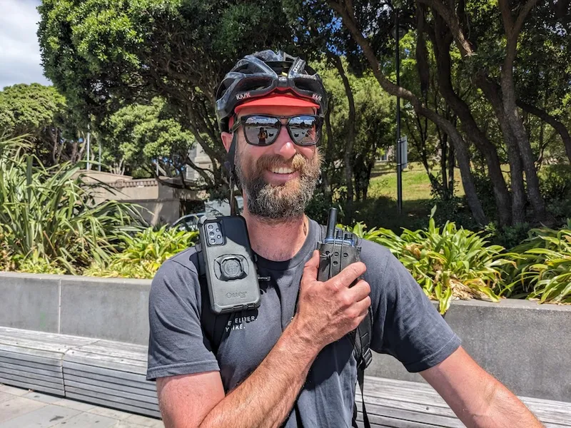 a smiling man with a transistor radio strapped to his shoulder