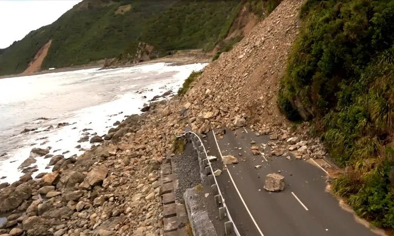 a narrow highway by some rugged coast, with a huge slip completely covering the road