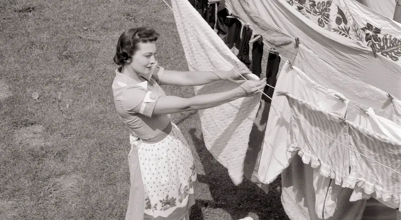 black and white 1950s photo of woman hanging out the washing