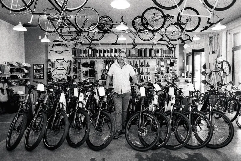 A man stands in his bicycle shop surrounded by bikes